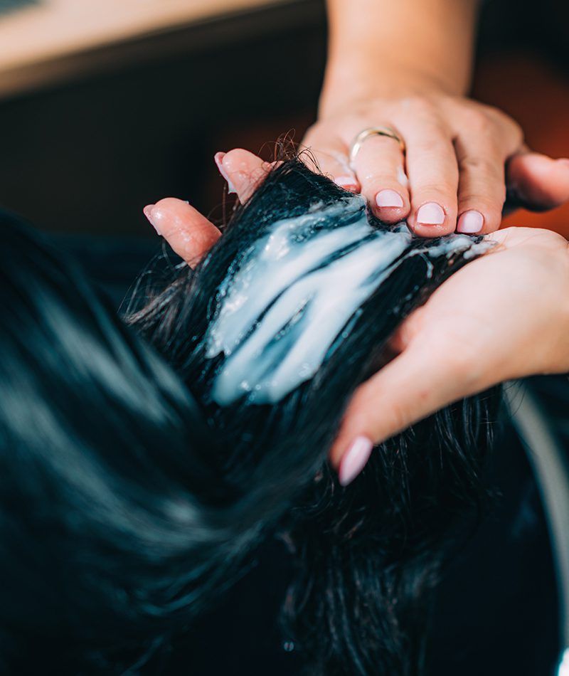 Primer plano del cabello mientras le están aplicando un tratamiento en el lavacabezas.