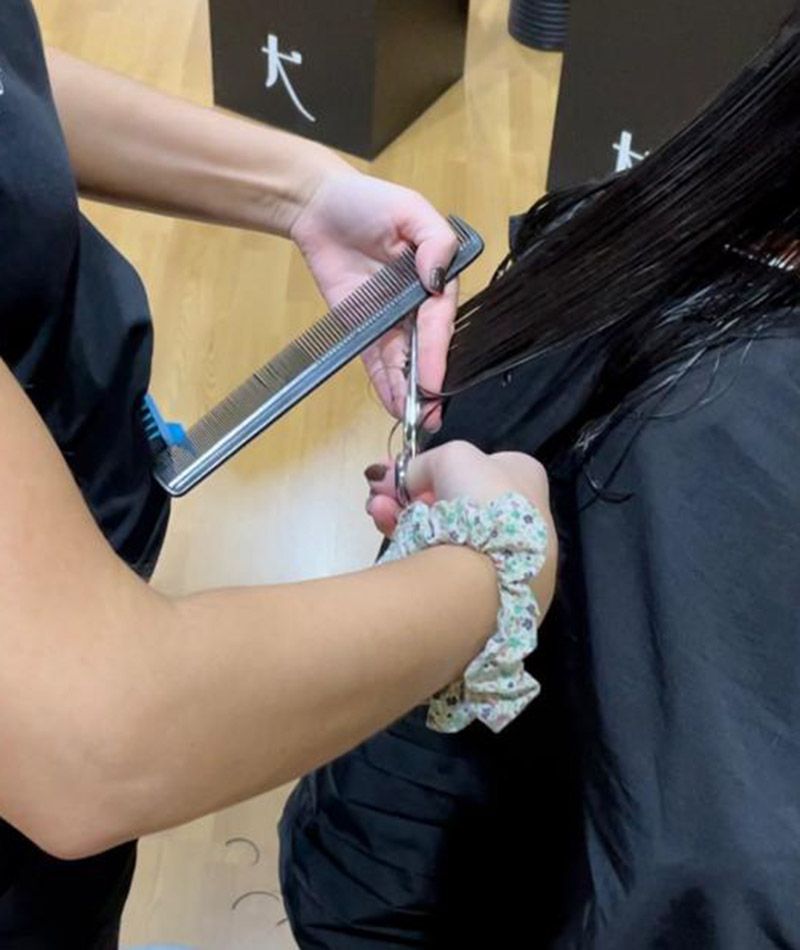 Unas manos de una peluquera cortando el pelo.