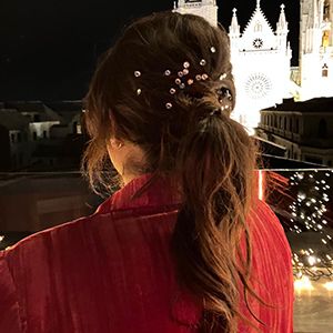 Chica con un recogido de coleta y brillantitos entre el pelo con la catedral de fondo.