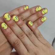 Manicura semipermanente. Las uñas están maquilladas en amarillo con unos detalles en verde.